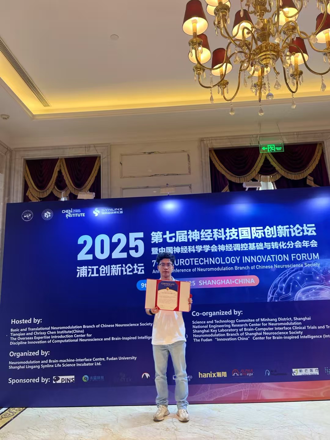 Holding a certificate in front of the Neurotechnology Innovation Forum backdrop