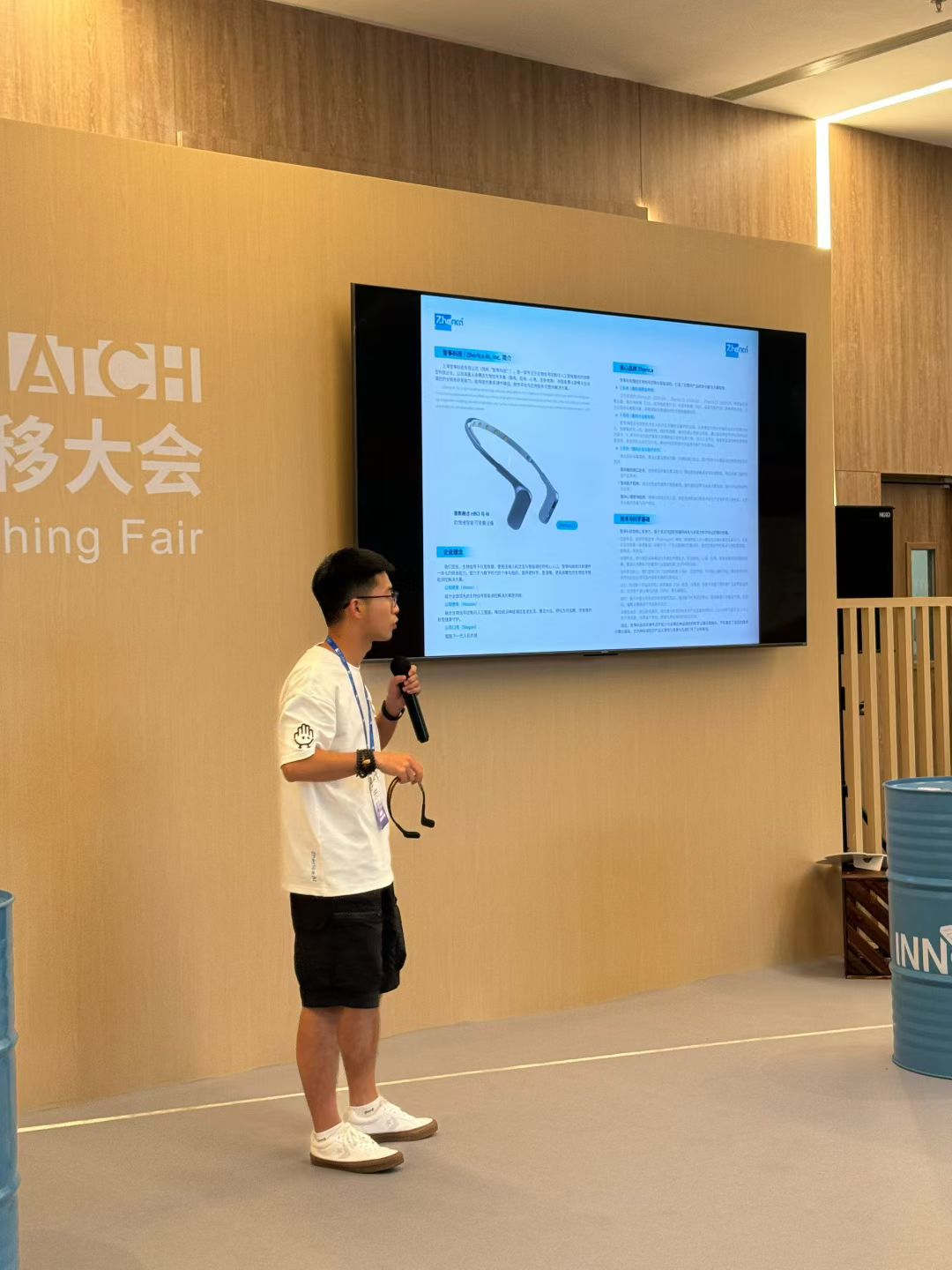 Speaking at a community event beside a large screen